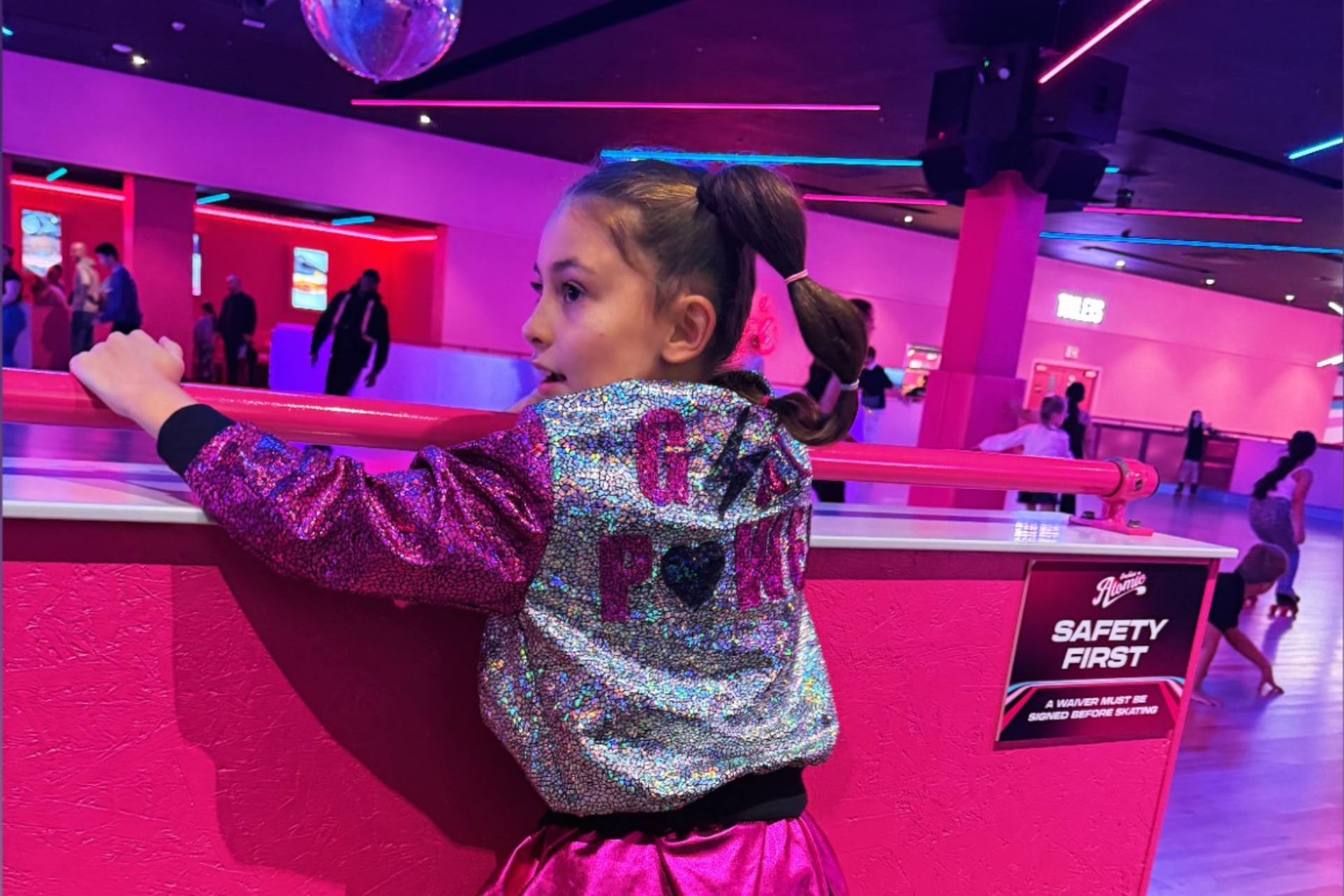 Young girl in a colorful indoor play area with pink and purple lighting jacket.